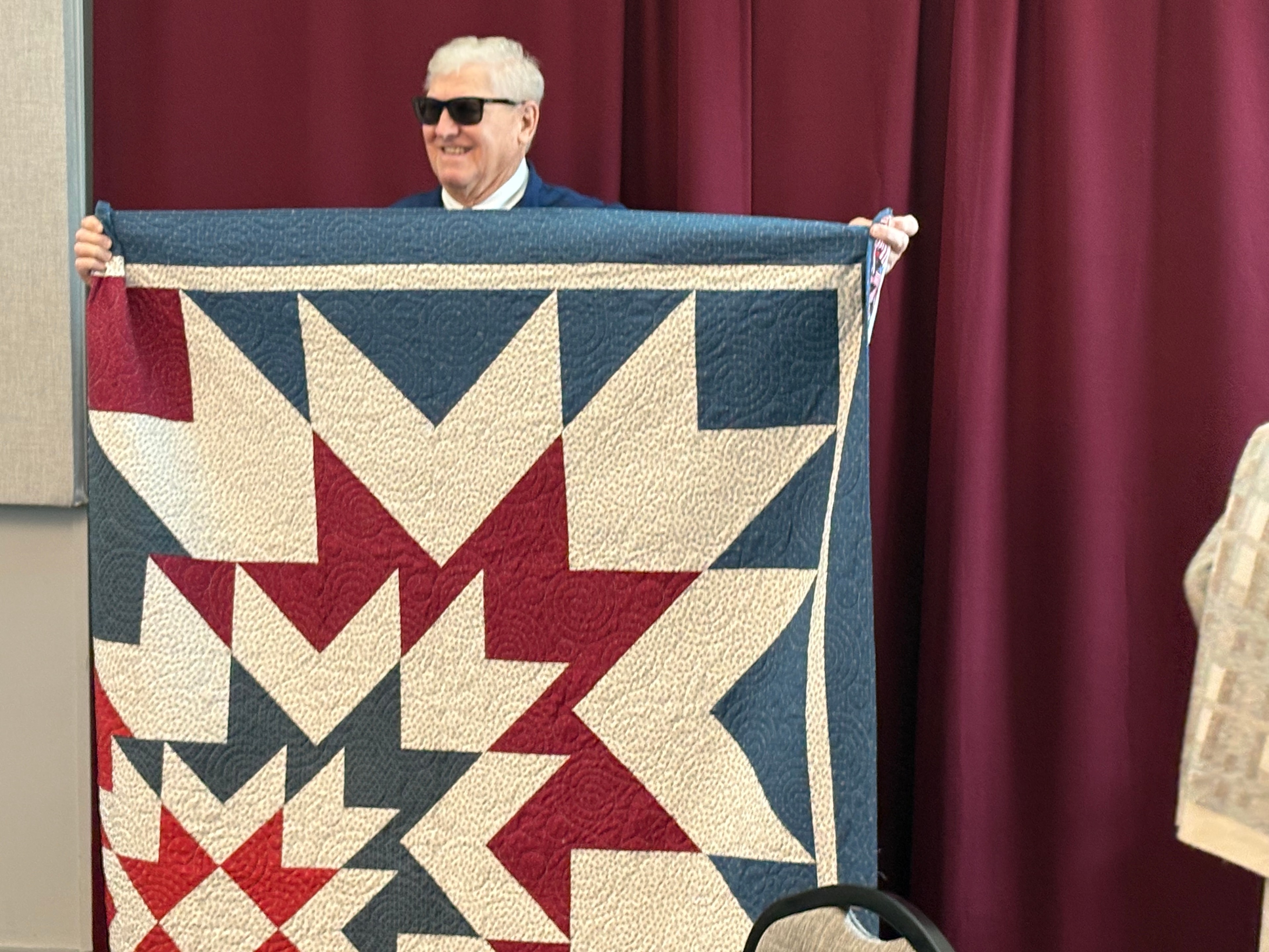 Chief Boyer holding the Military Service Quilt handcrafted by the St. James Quilters