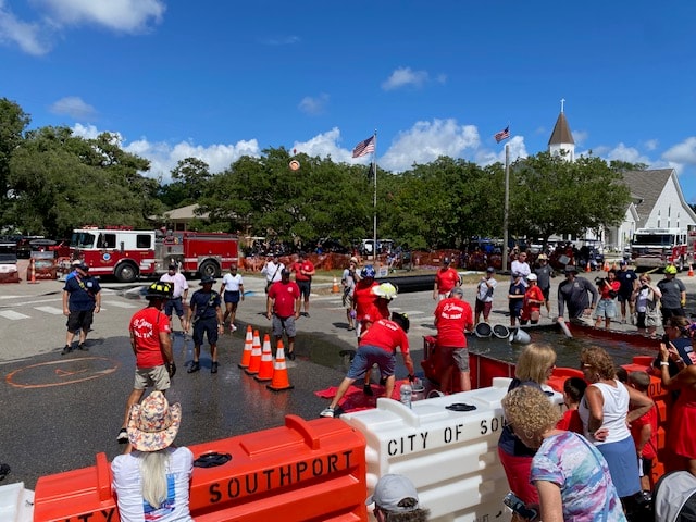 Wide view of the Bucket Brigade event with SJFD volunteers and spectators lining the City of Southport barriers