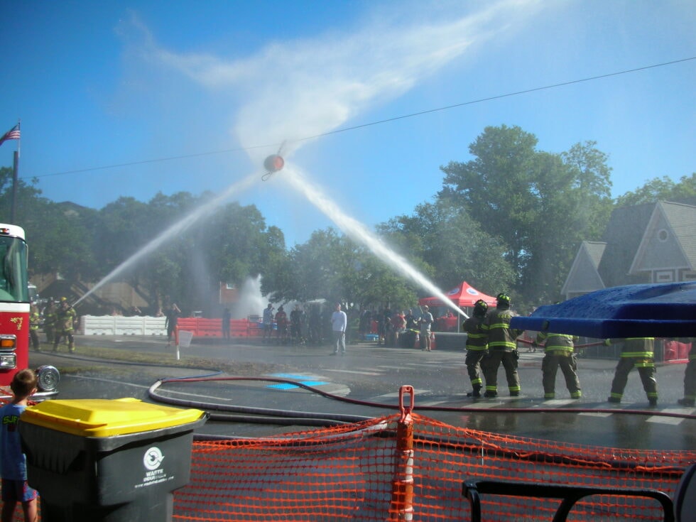 Two competing teams cross streams of water in a target challenge at the Southport firefighter competition