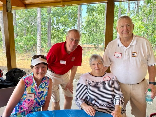 Four SJFD volunteers and guests pose together at a picnic table under the Woodlands Park Pavilion