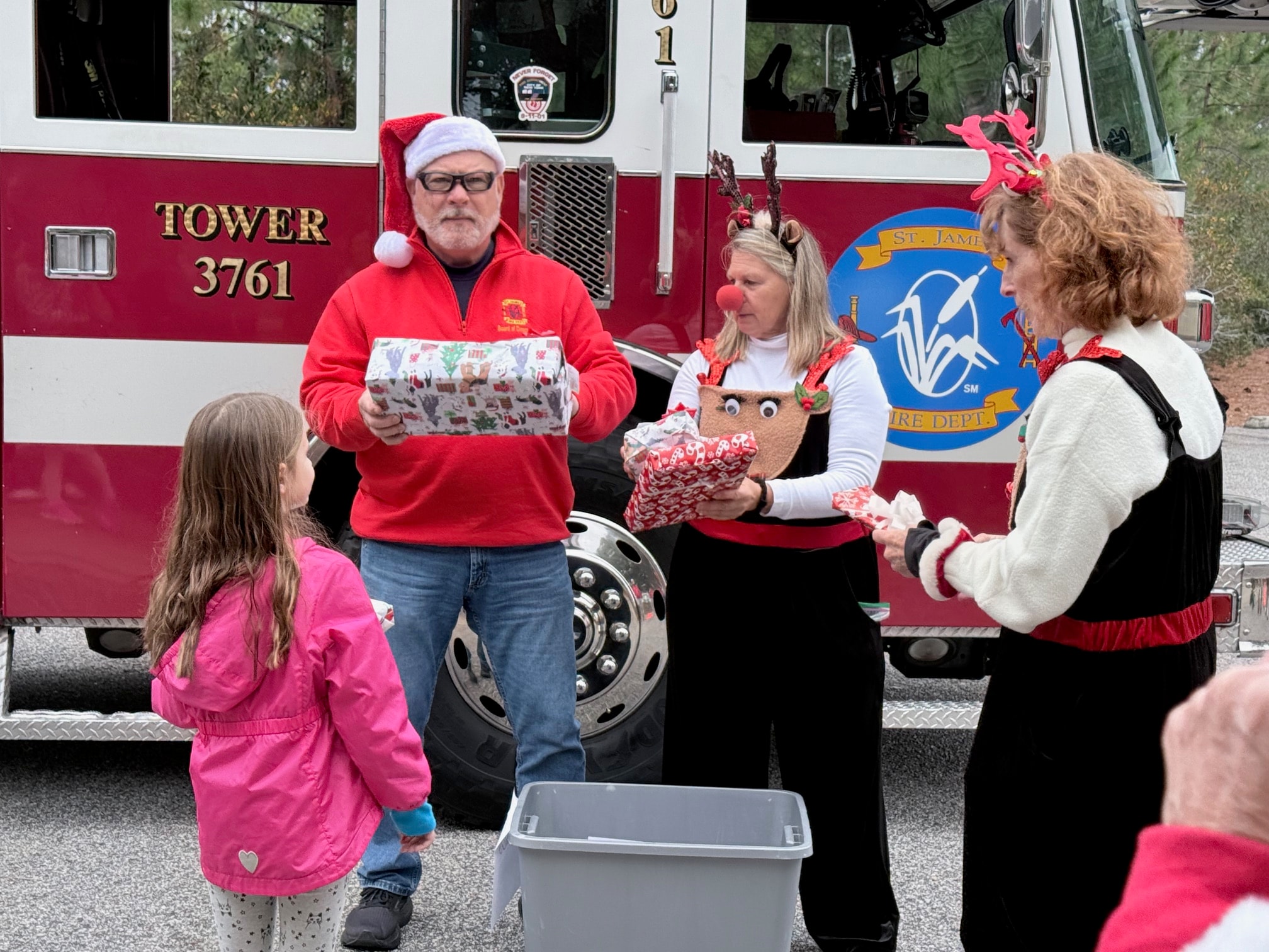 SJFD volunteers handing wrapped gifts to children in front of Tower 3761